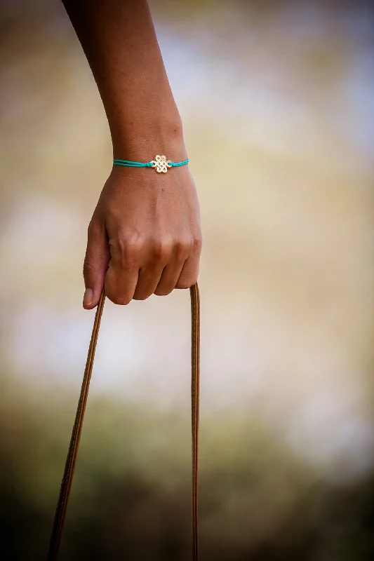 Turquoise cord bracelet with gold endless knot charm